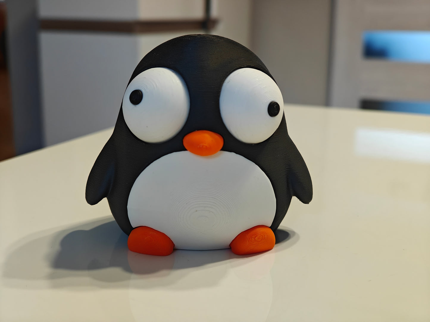 Small penguin figure with googly eyes styled on a desk next to a coffee mug