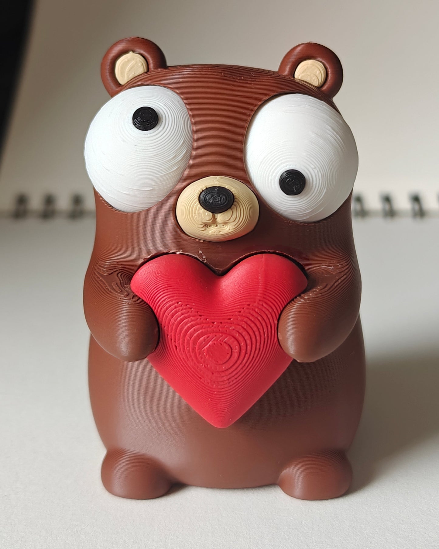 Close-up of a small bear figure holding a heart with big movable googly eyes
