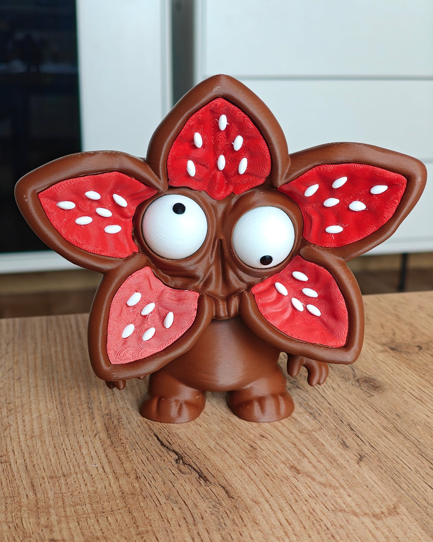 Flower-face monster figure with big movable googly eyes, front view on white background