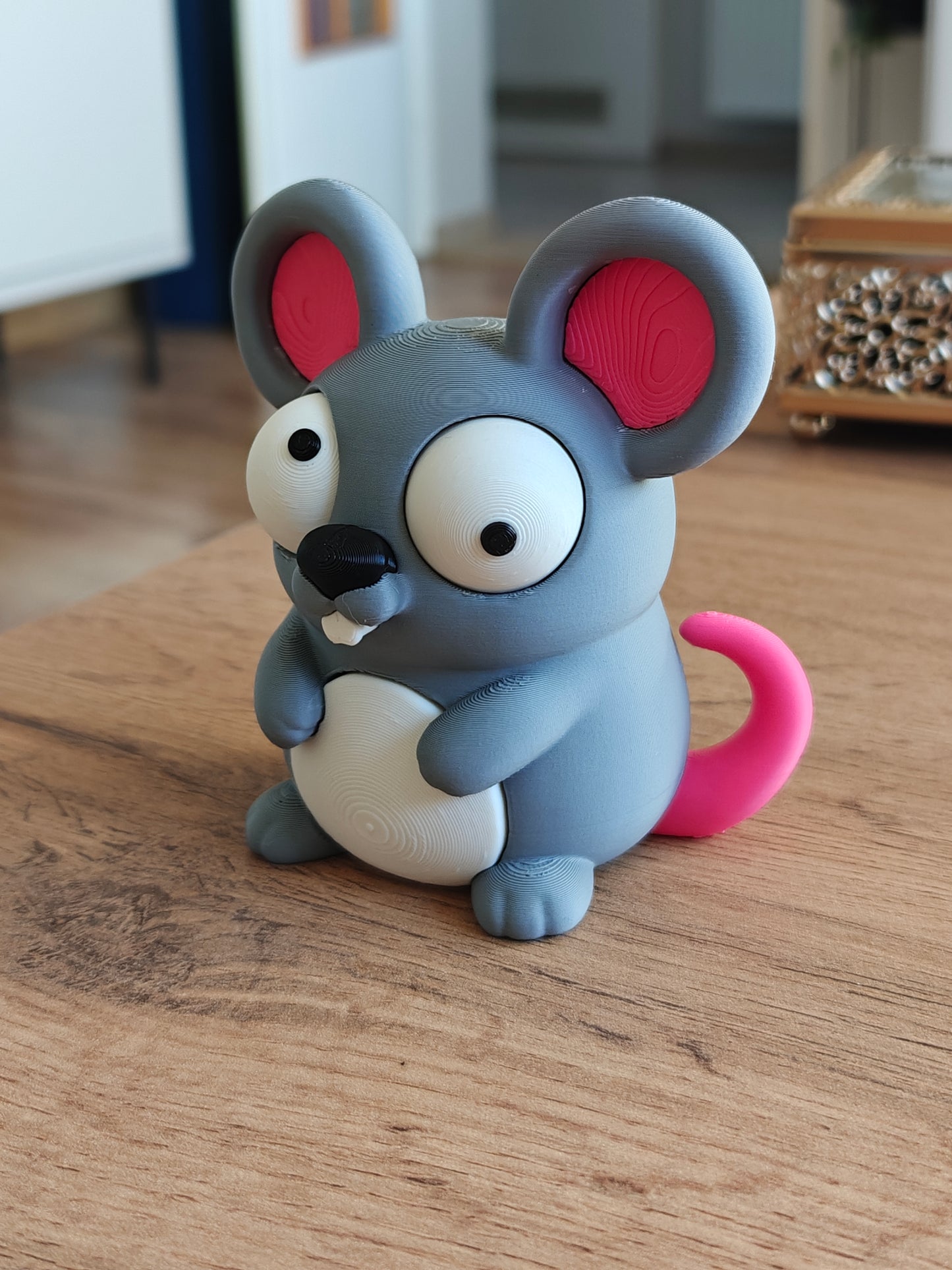 Close-up of a small cartoon mouse figure with large movable googly eyes and a tiny smile