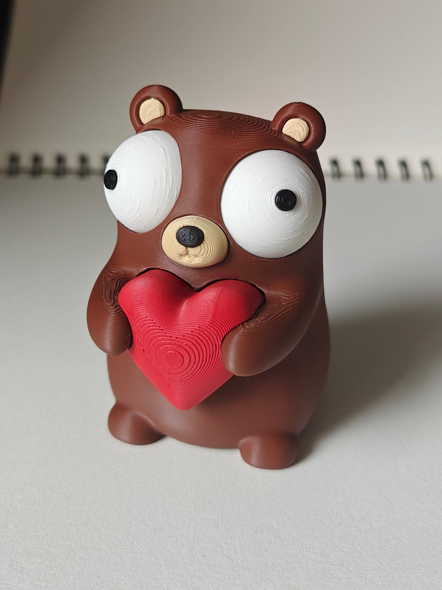 Close-up of a small bear figure holding a heart with big movable googly eyes