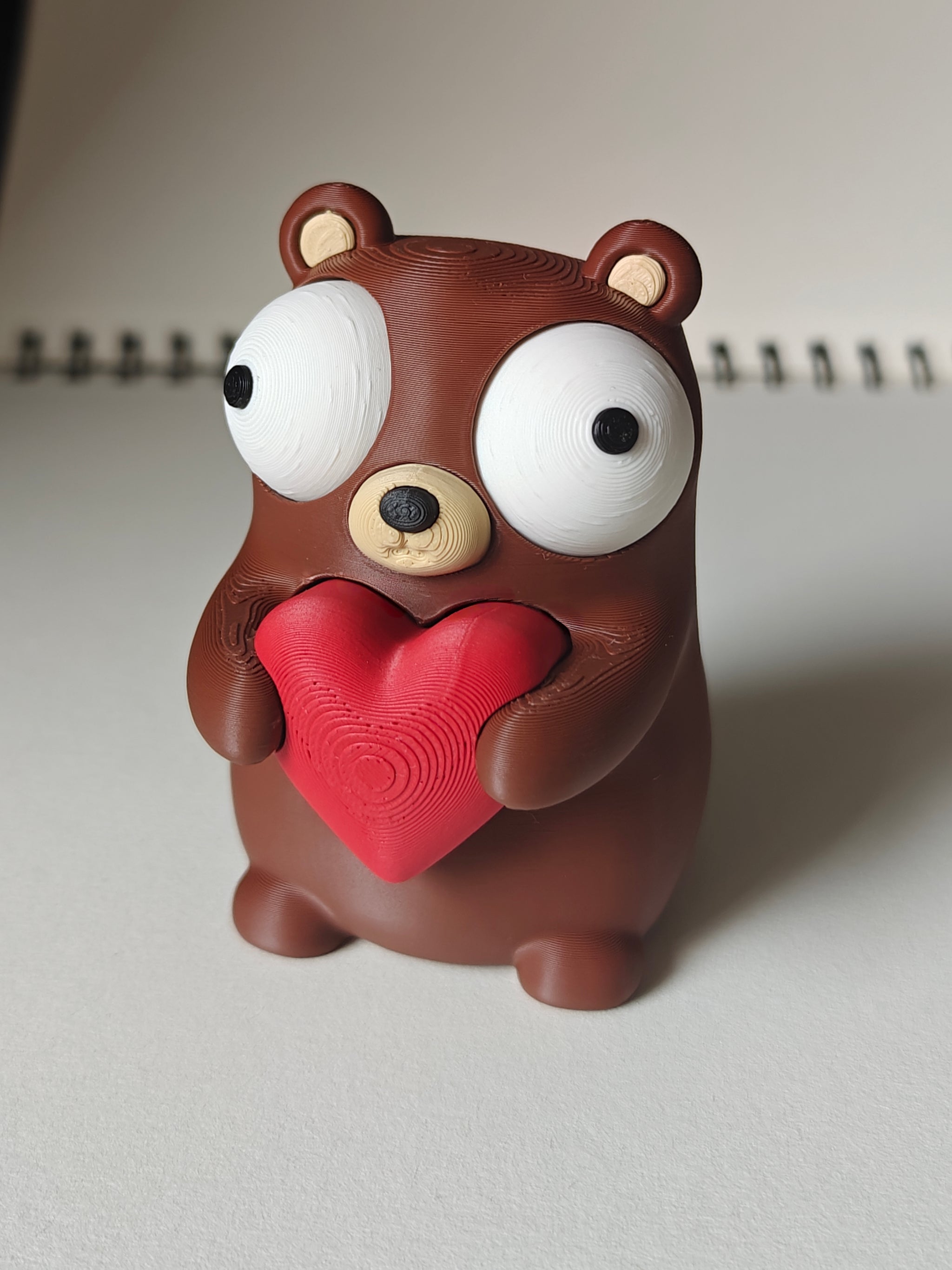 Close-up of a small bear figure holding a heart with big movable googly eyes