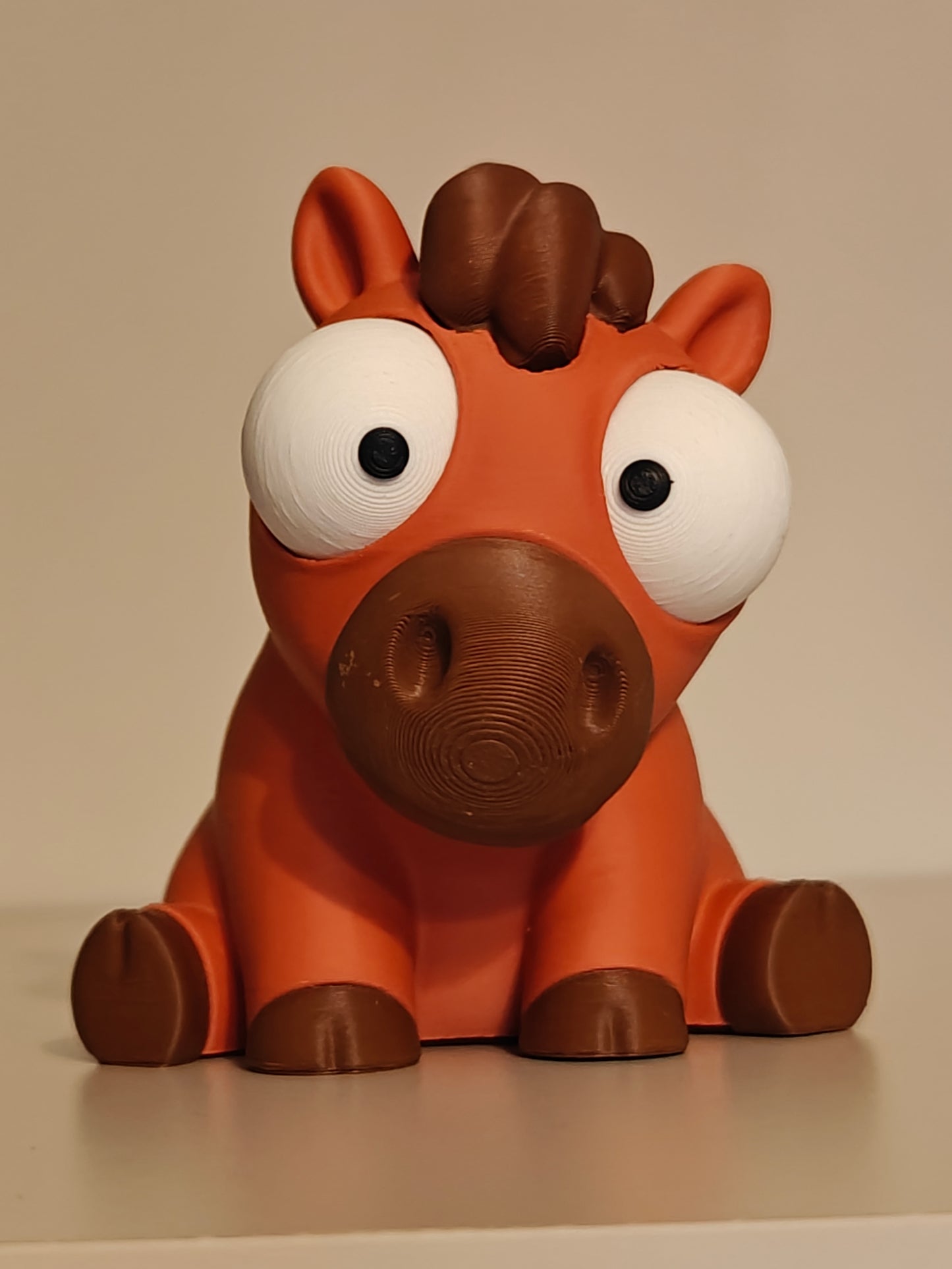 Close-up of goofy horse figurine with big movable googly eyes on a white surface