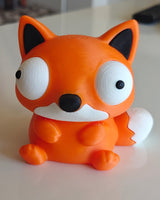 Foxie goofy fox figure sitting on a desk next to a plant and coffee mug