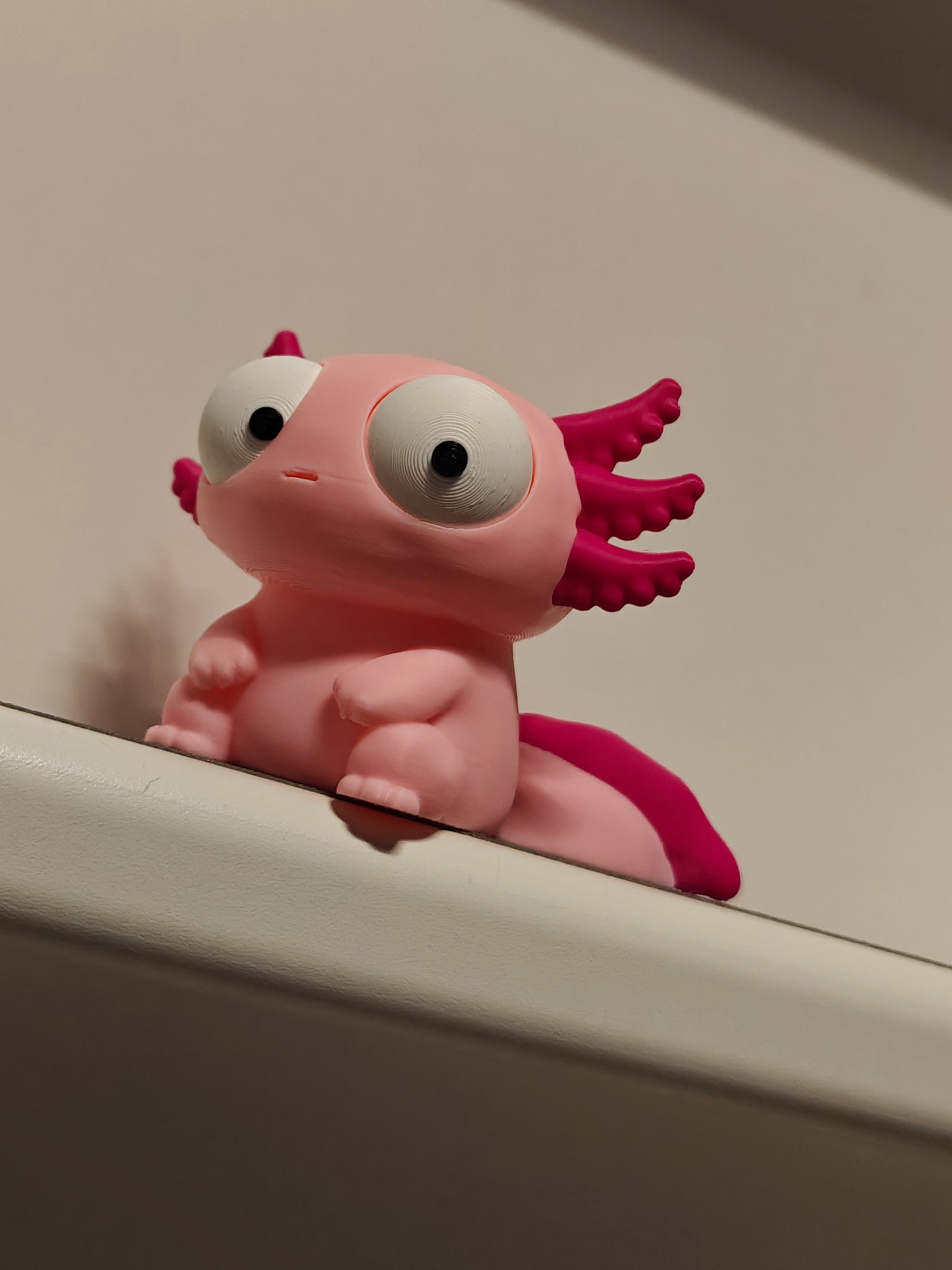 Goofy axolotl figure with large movable googly eyes, front view on white background