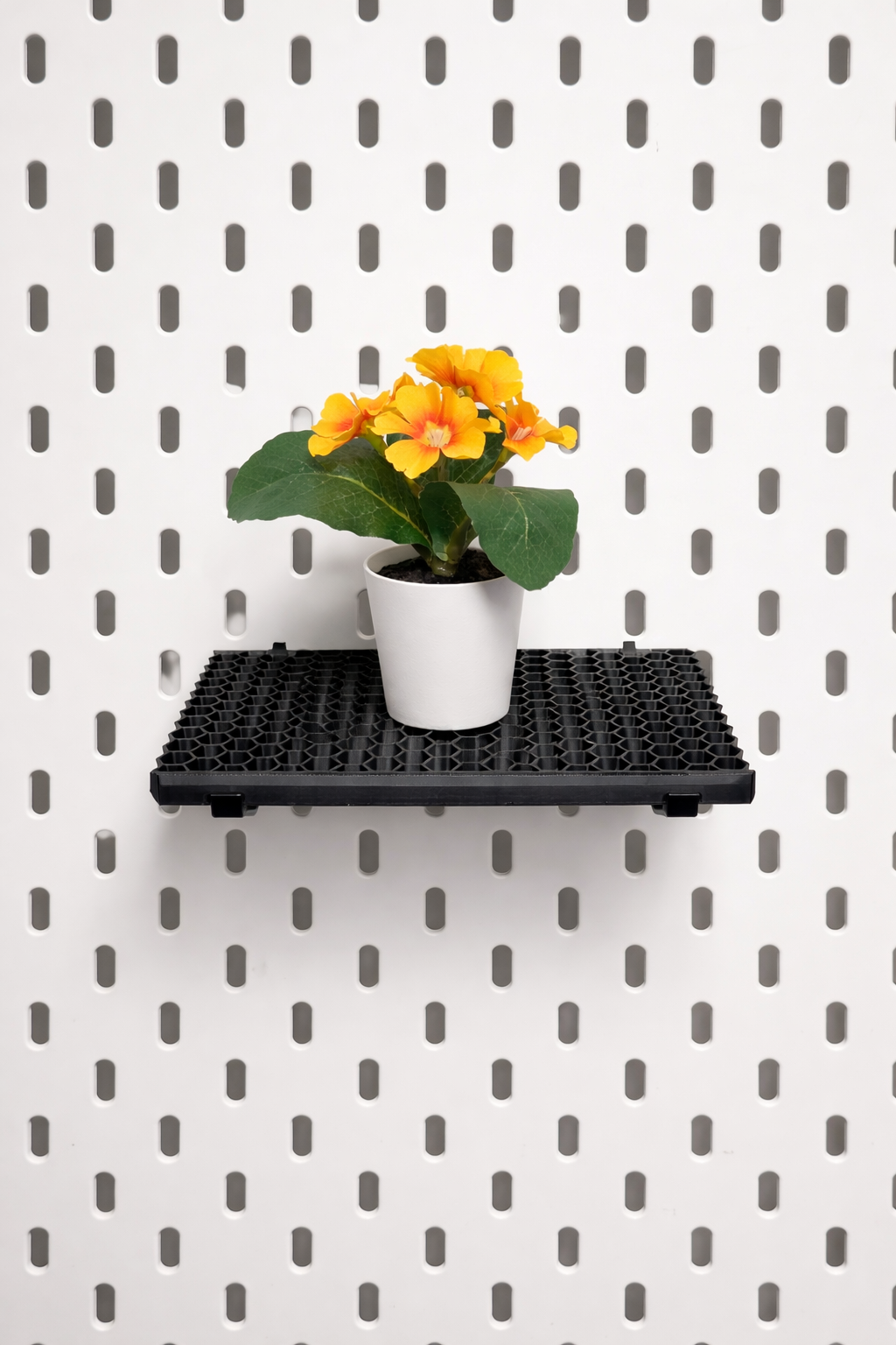 Modular white pegboard shelf designed for IKEA Skadis system, displaying plants and decorative items