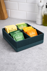 Deep teal-green ribbed tea bag organizer with four square compartments on white surface