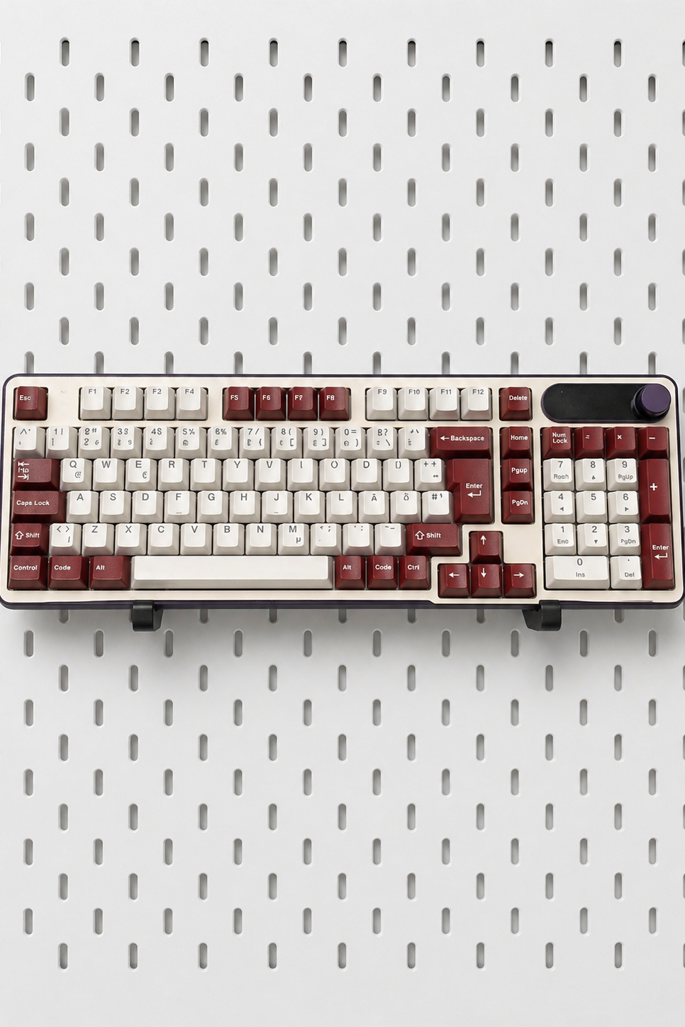 Two black keyboard holders mounted on white IKEA Skadis pegboard displaying mechanical keyboards