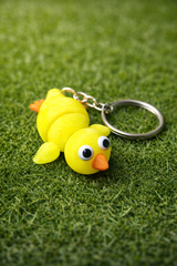 Bright neon yellow 3D printed chicken keyring with orange beak and cheerful expression