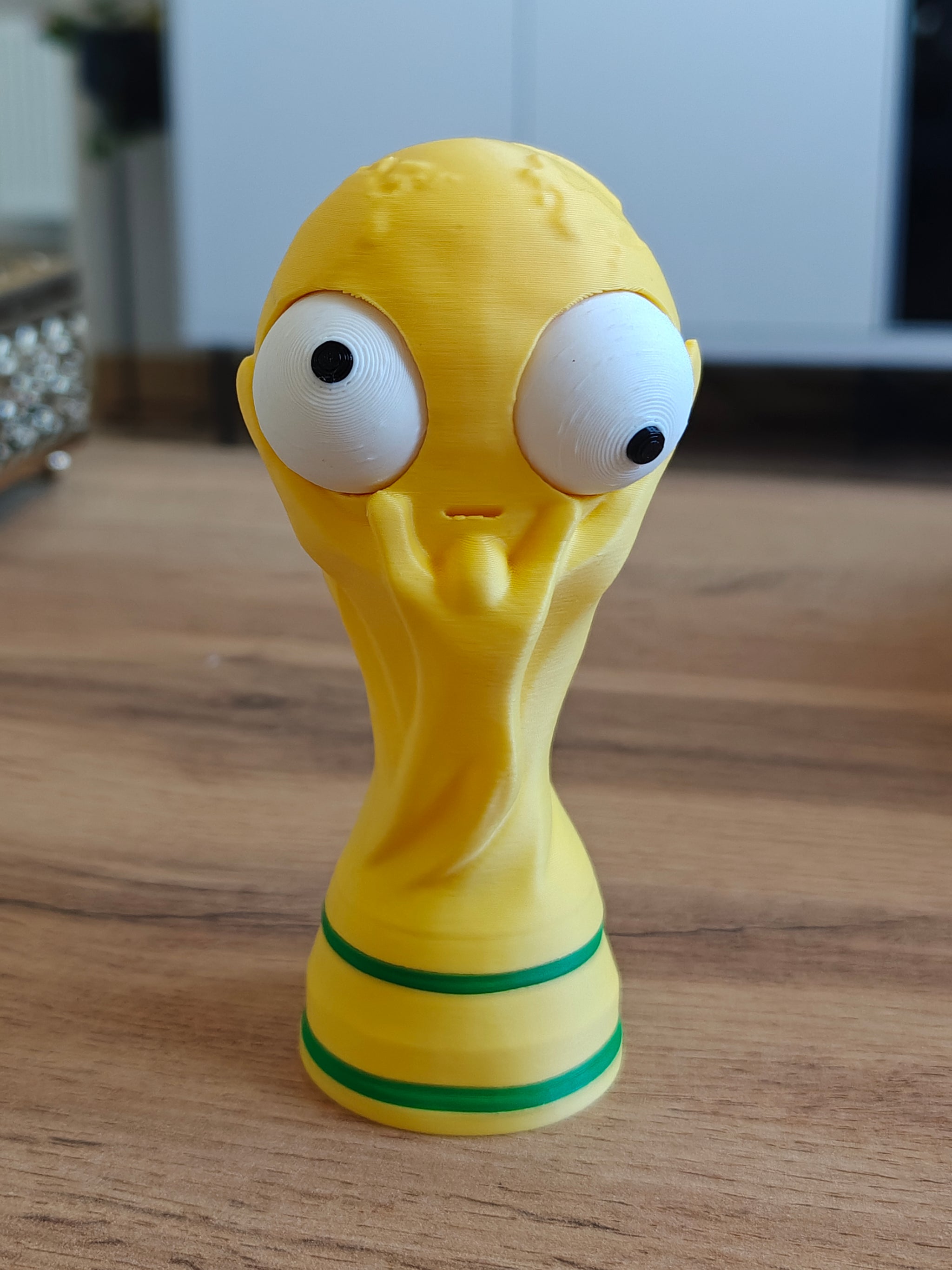 Close-up of goofy world cup trophy figure with large movable googly eye, front view