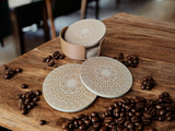 Six Greek design coasters stacked in matching holder on wooden table