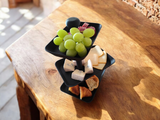 Three tier serving tray styled on a kitchen counter with snacks and pastries