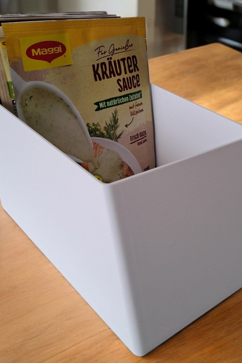 White kitchen ingredient organizer with angled interior and ribbed base, close-up view