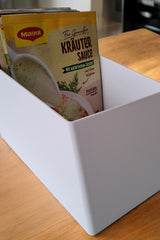 White kitchen ingredient organizer with angled interior and ribbed base, close-up view