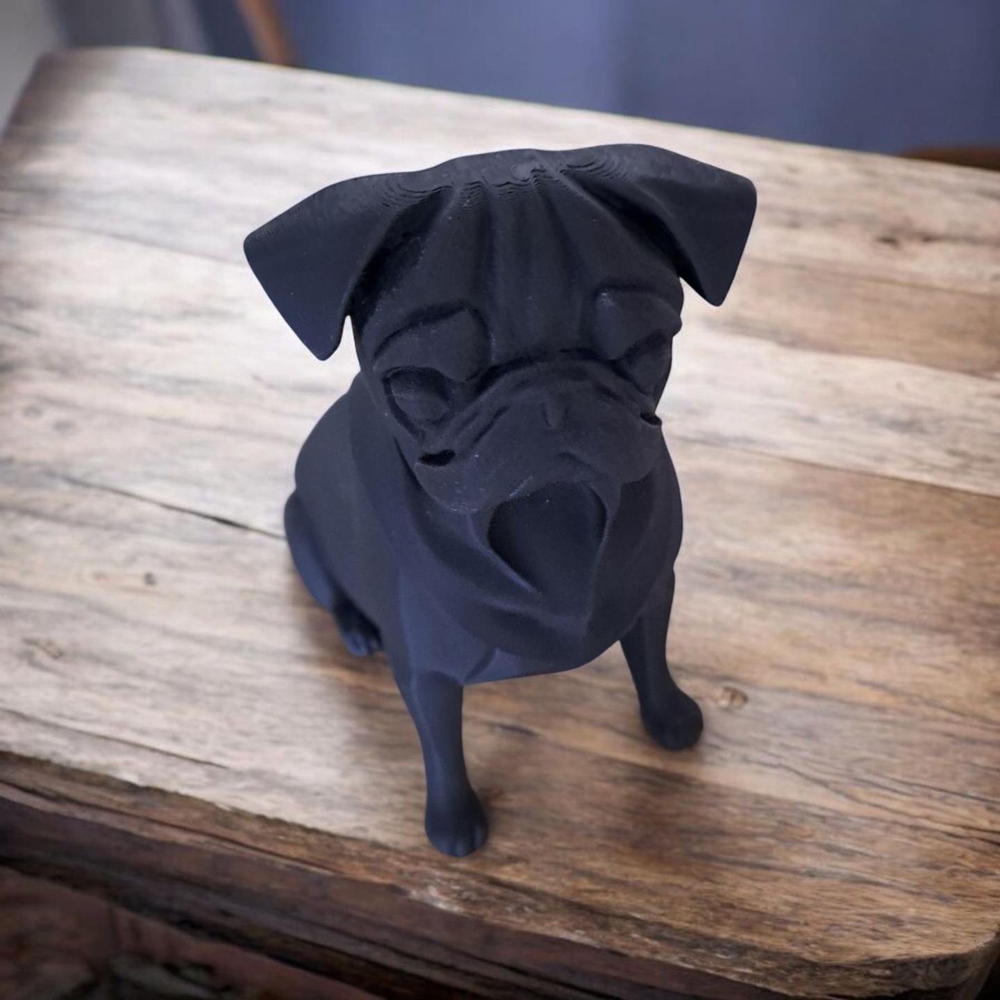 Close-up of minimalist pug sculpture showing smooth matte black surface