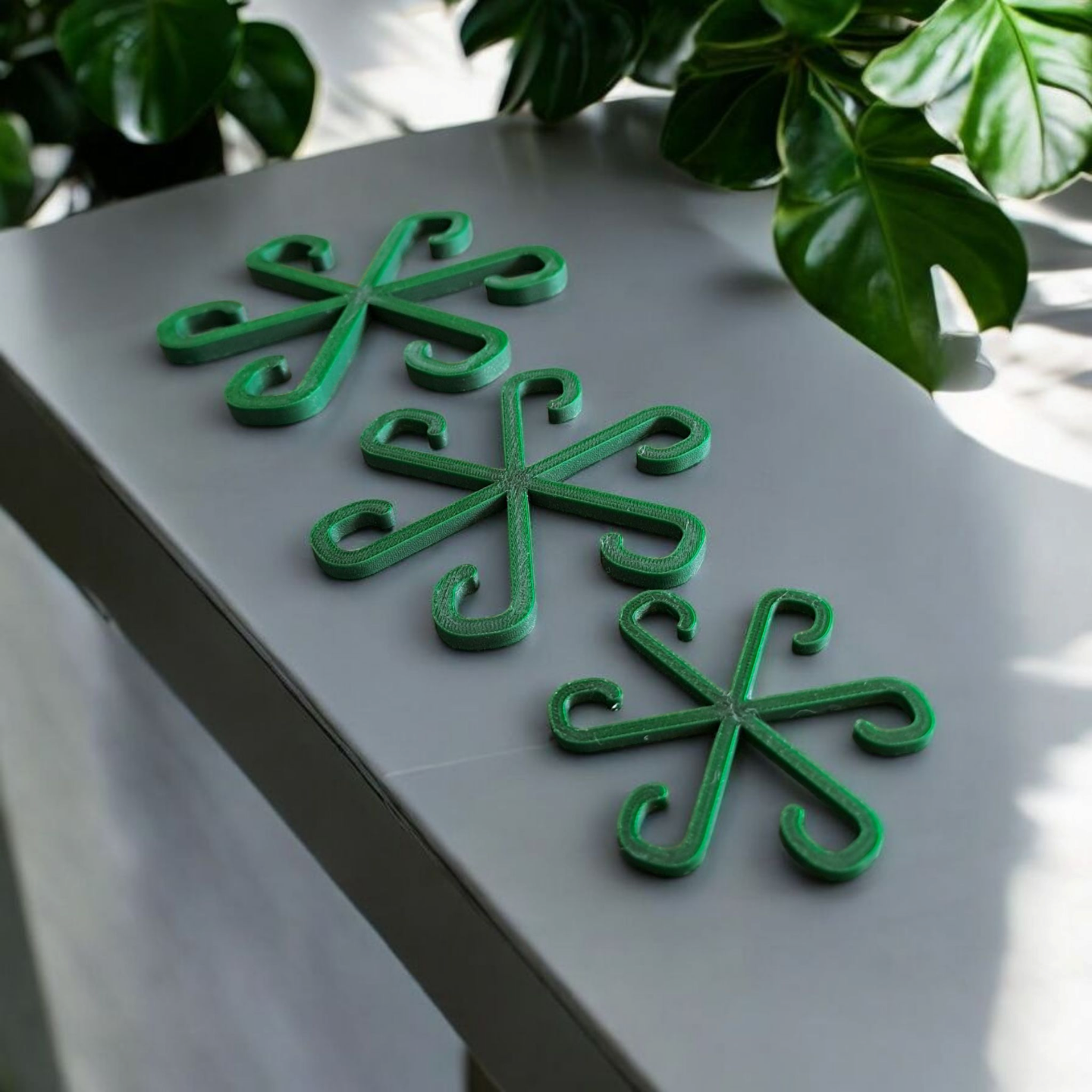 Three plant support hooks installed in potted plants on a bright windowsill