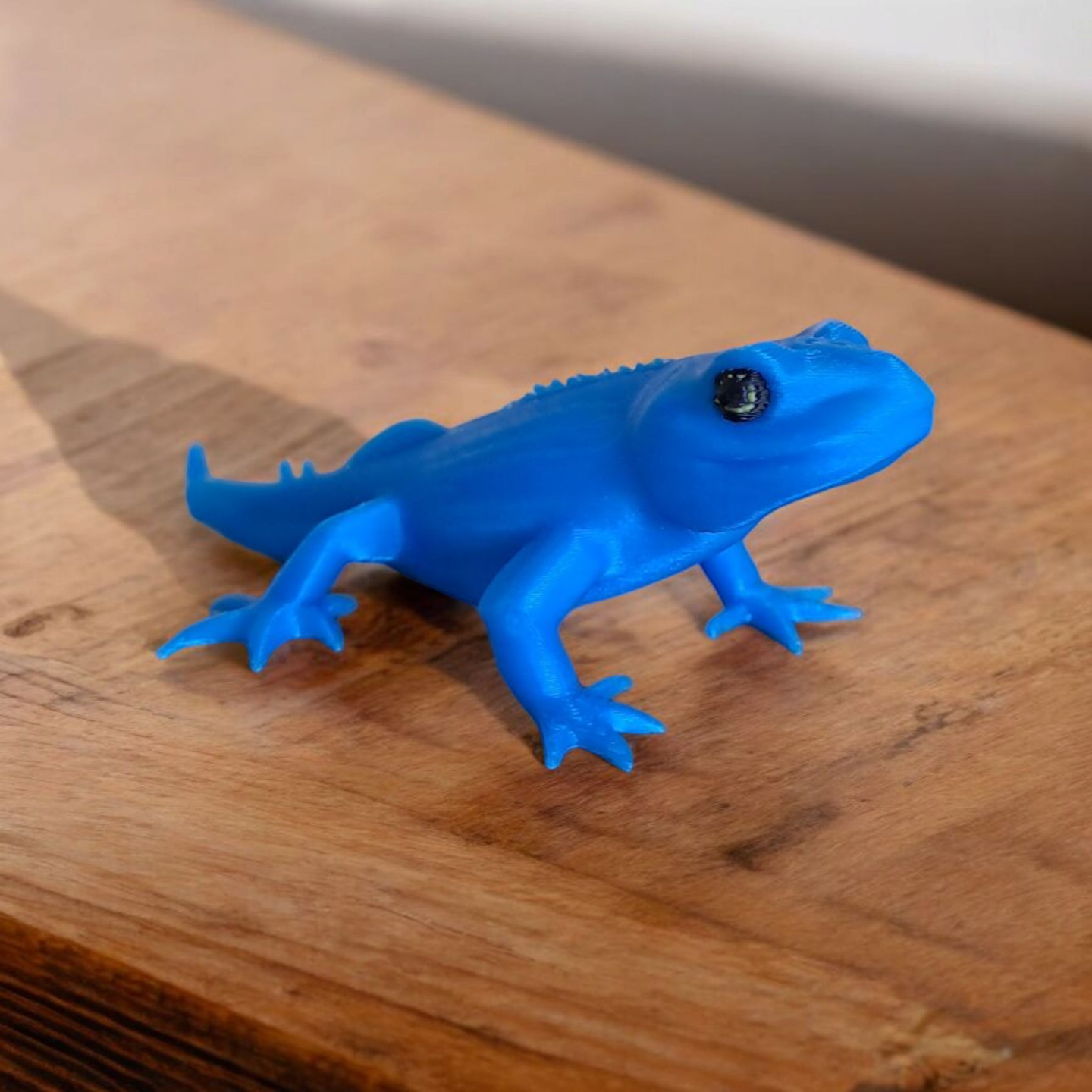 Small gecko lizard figurine displayed on a desk shelf beside minimalist decor
