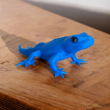 Small gecko lizard figurine displayed on a desk shelf beside minimalist decor