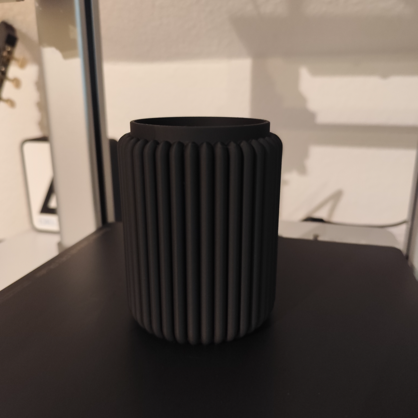 Ribbed pencil holder on desk holding pens and pencils in morning light