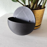 Wall-mounted ball plant pot displayed in a living room corner with trailing green plant