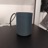 Ribbed toothbrush holder on bathroom counter holding brushes and personal items