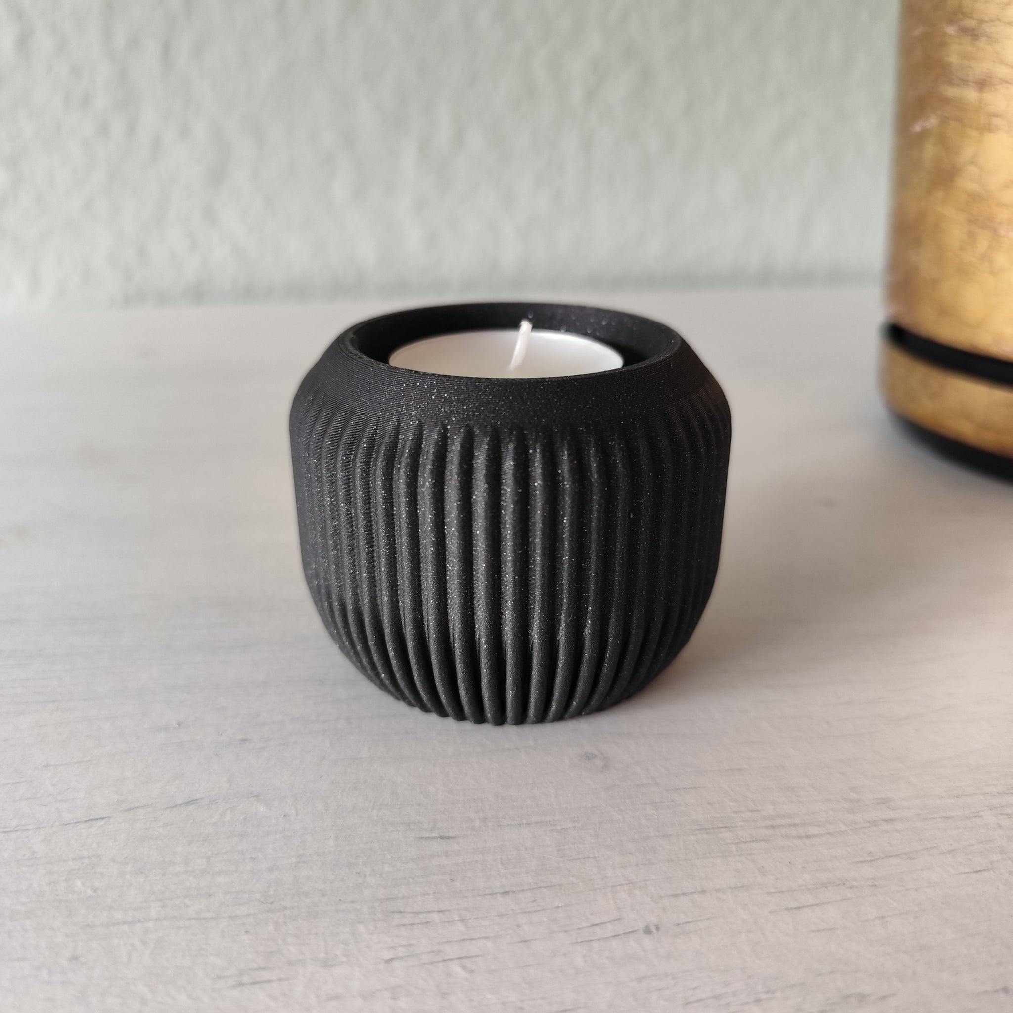 Minimalist tealight holder lit with warm LED tea light on wooden shelf