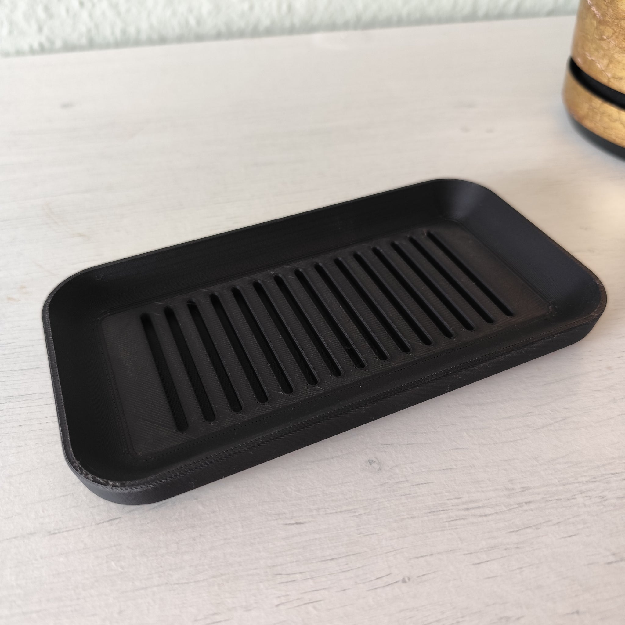 Soap dish placed on bathroom sink with soap bar and water droplets