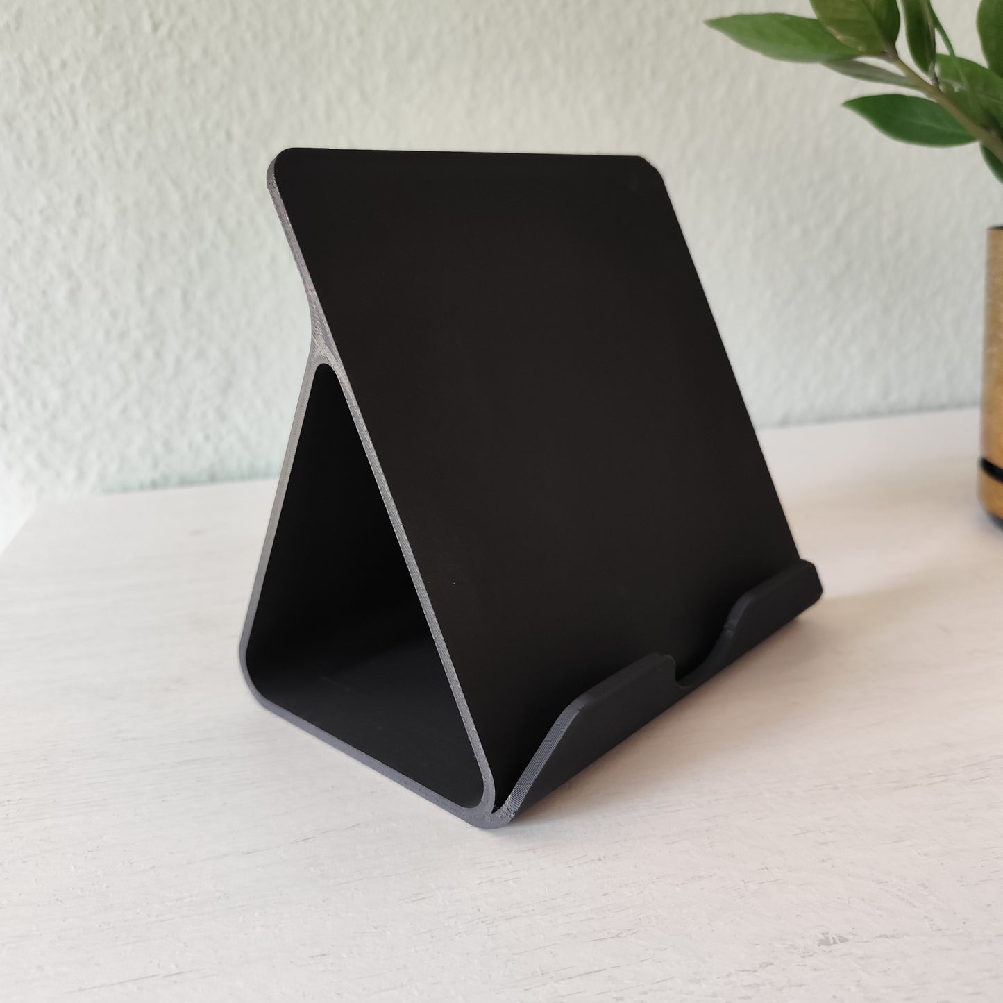 Tablet held in iPad stand on a clean desk next to workspace accessories