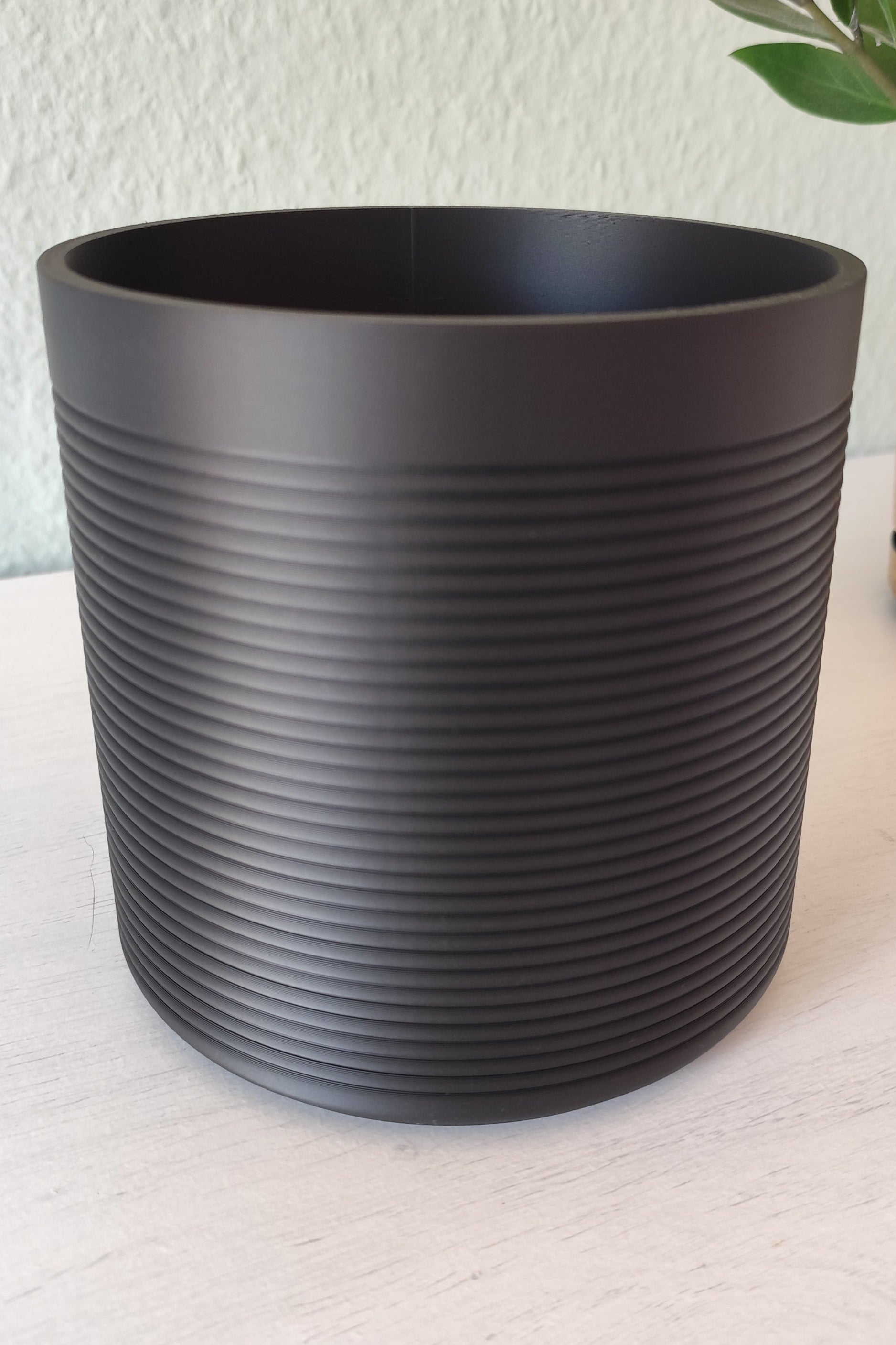 Ribbed kitchen utensil holder on wooden countertop, styled with fresh herbs nearby