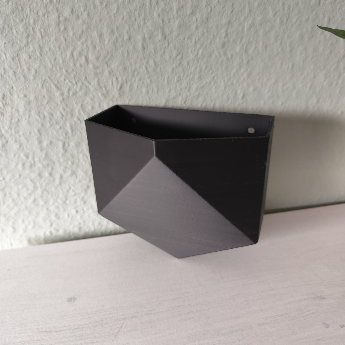 Low poly wall planter mounted on white wall with small potted plant