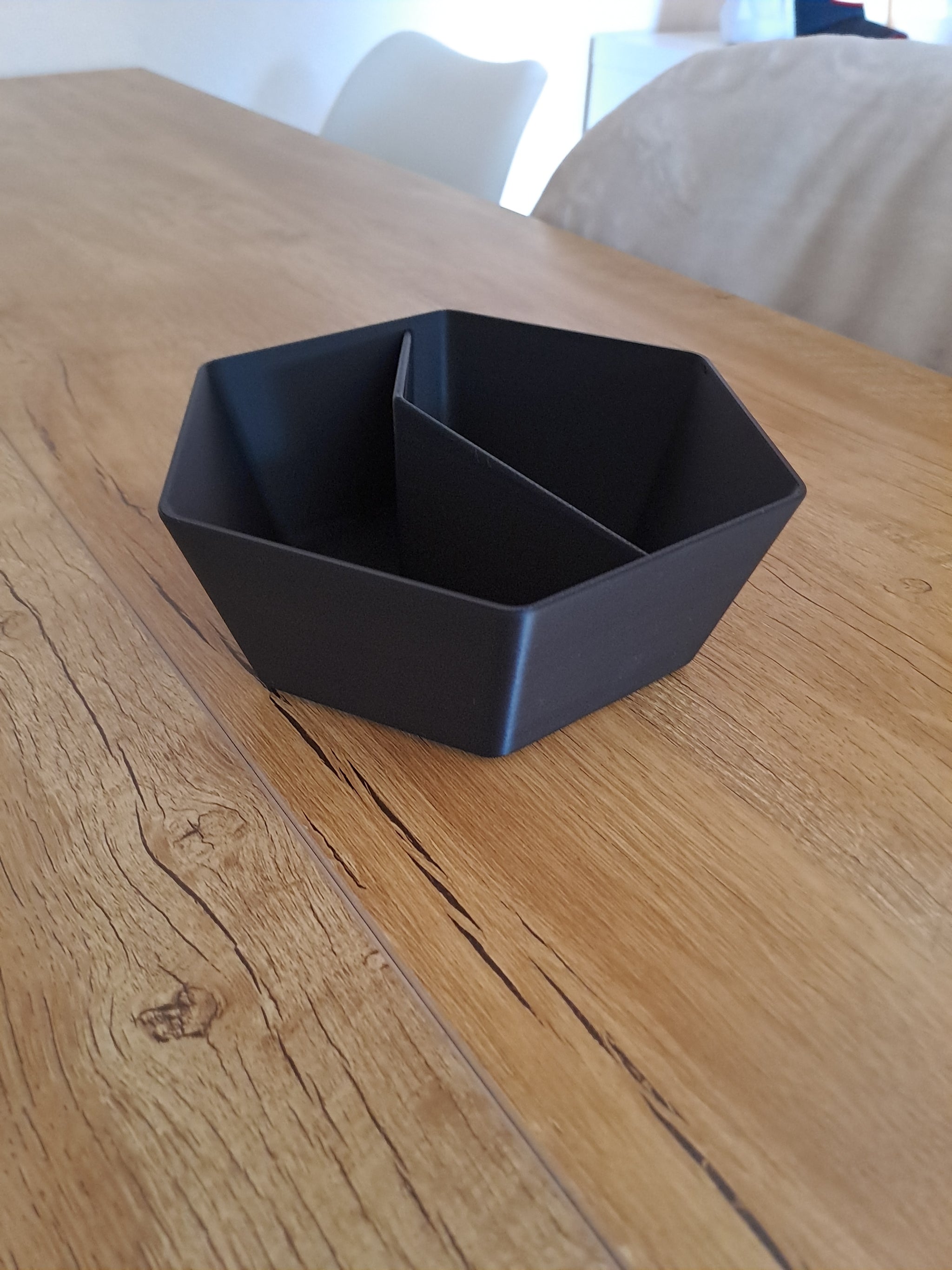 Two-compartment pistachio bowl styled on wooden surface with scattered nuts and shells