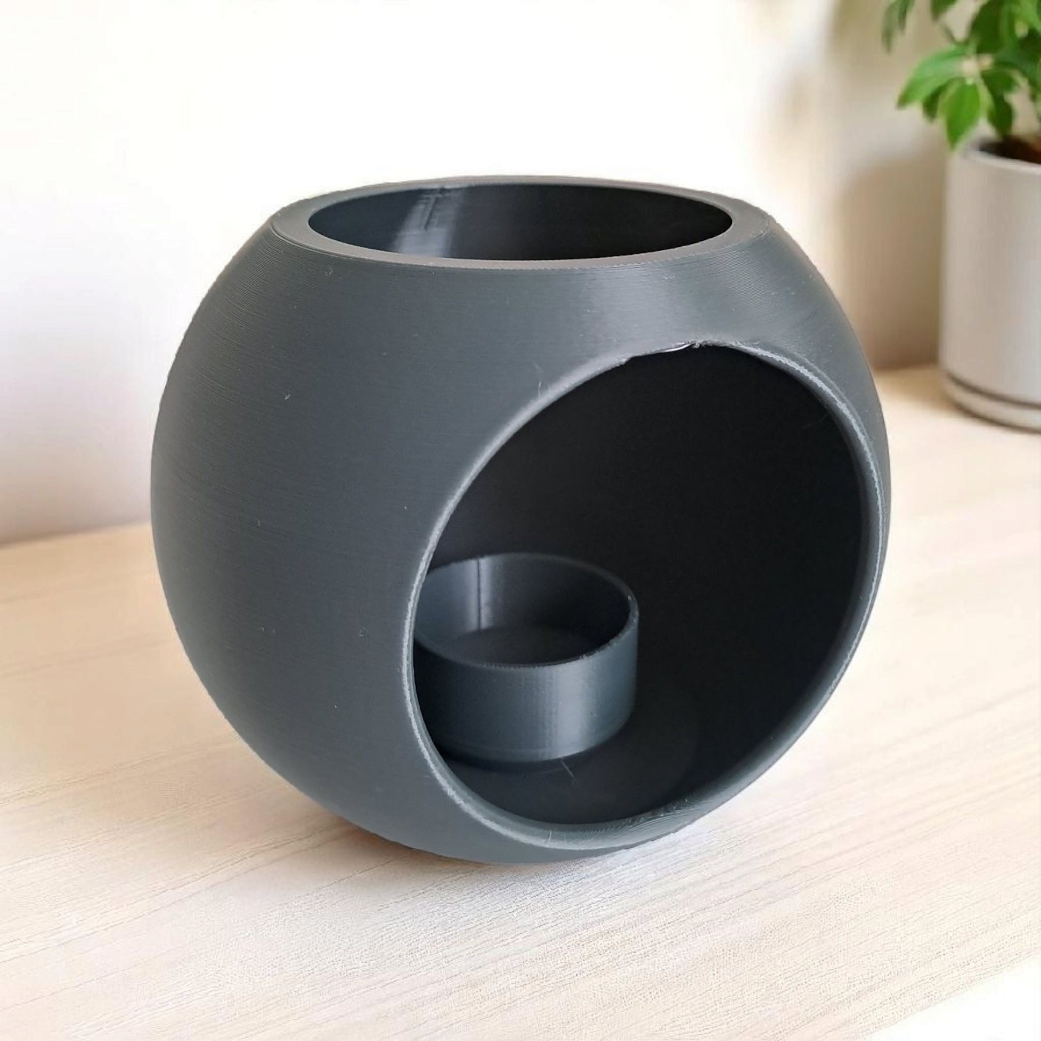 Spherical LED tealight holder in white, close-up showing smooth geometric form