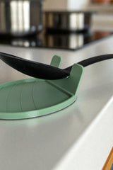 White spoon rest holding a wooden spoon, close-up view of the curved lip design