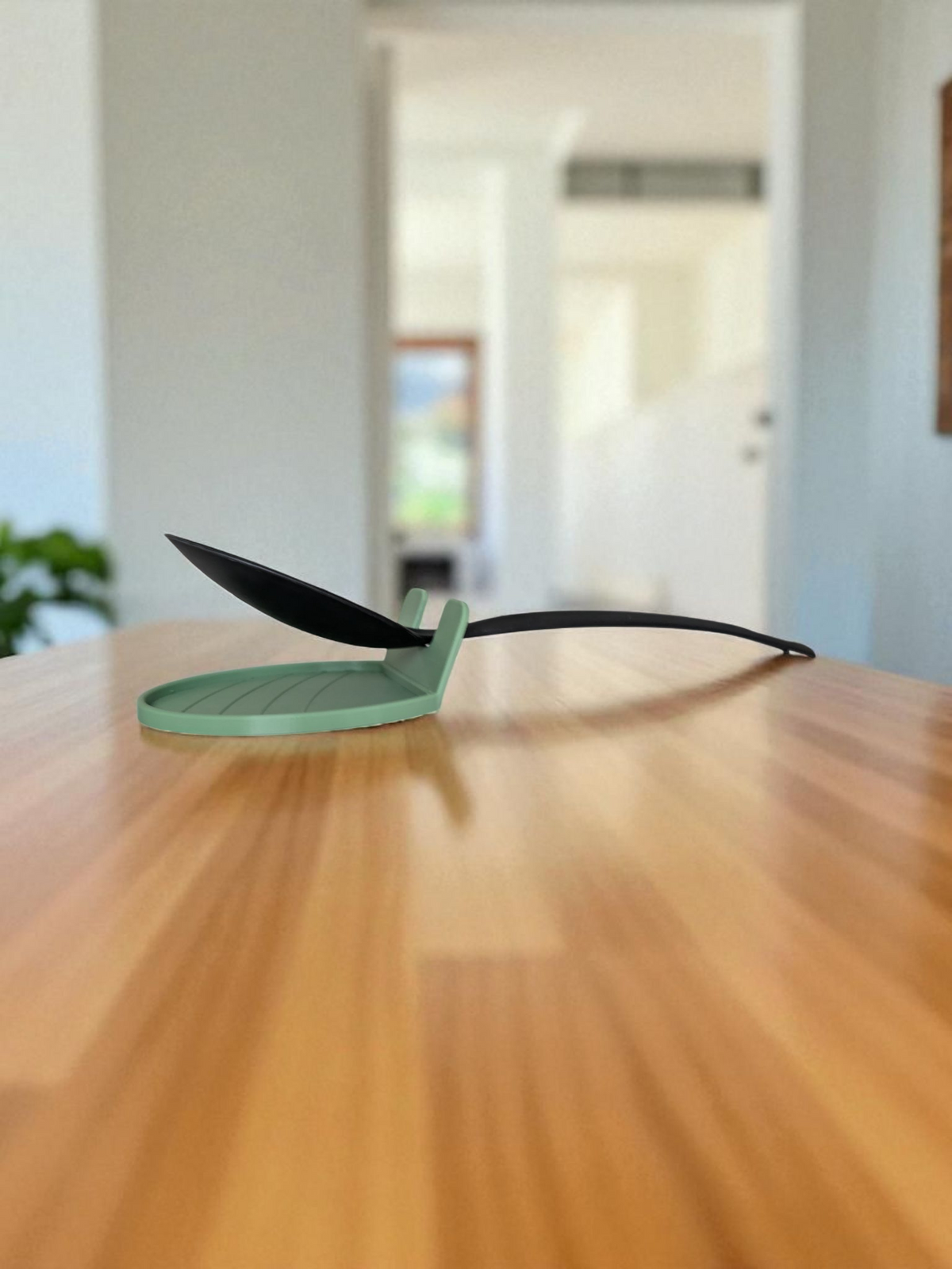 CookSitter spoon rest positioned beside a stovetop with a cooking spoon resting inside