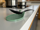 White spoon rest holding a wooden spoon, close-up view of the curved lip design