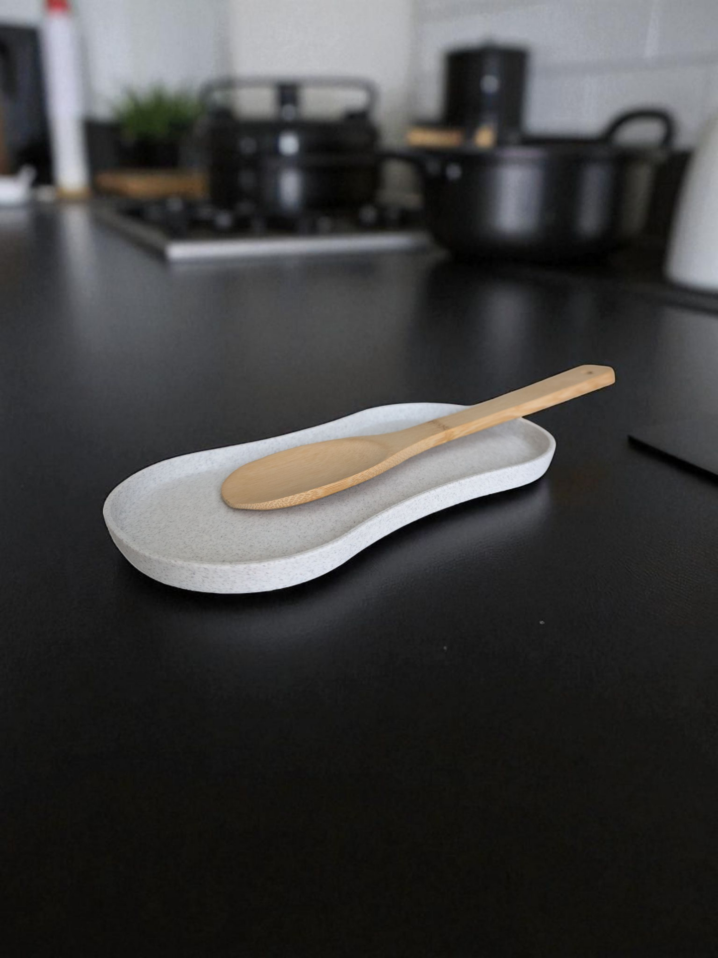 Spoon rest on kitchen counter holding wooden spatula and cooking spoon