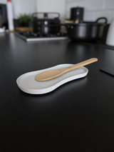 Spoon rest on kitchen counter holding wooden spatula and cooking spoon