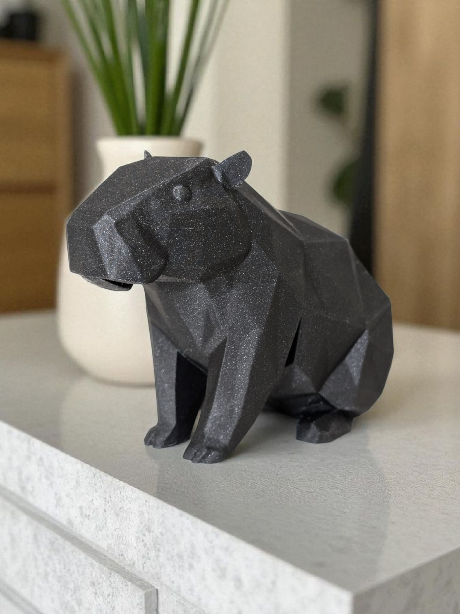 Minimalist capybara figure displayed on a white shelf in a bright room