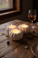 Autumnal pumpkin tealight holder with lit candles on a wooden shelf