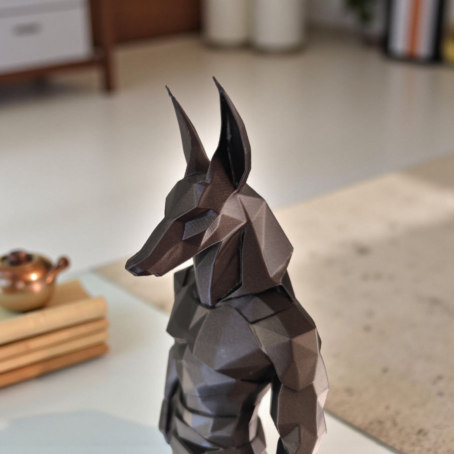 Low poly anubis statue displayed on a light shelf with minimal decor styling