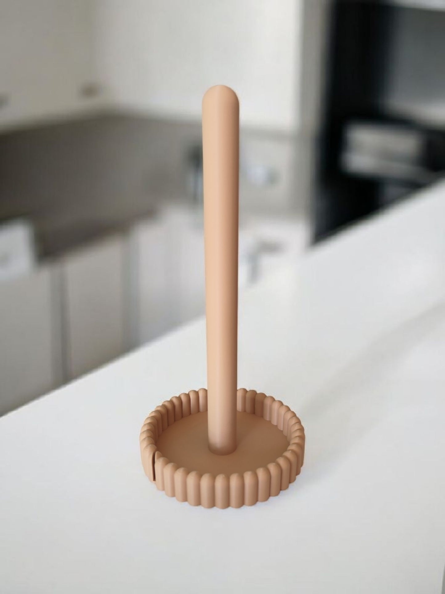 Paper towel holder on kitchen counter next to white coffee cup and green plant