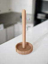 Paper towel holder on kitchen counter next to white coffee cup and green plant