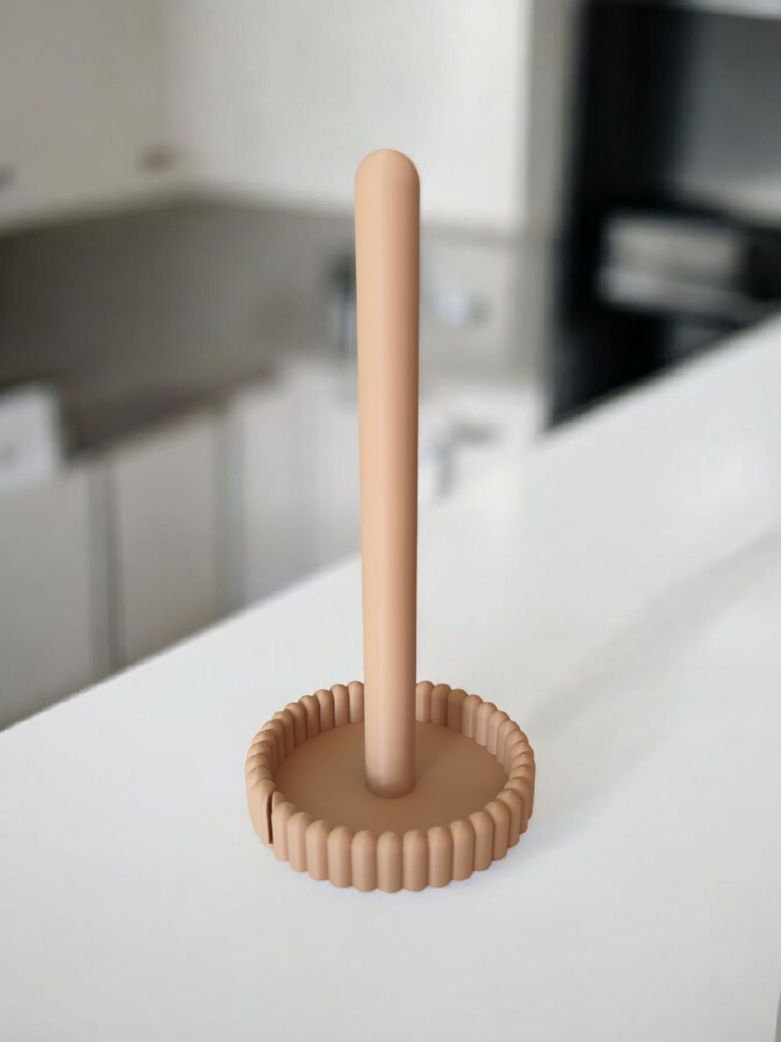 Paper towel holder on kitchen counter next to white coffee cup and green plant