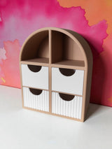 Small jewelry shelf with ribbed drawers styled on a bedroom dresser next to books