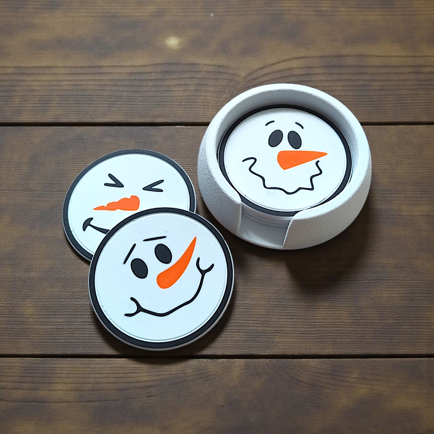 Six snowman coasters with different faces stacked in matching holder