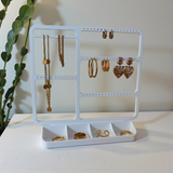 Jewelry organizer mounted above a dresser with earrings and delicate necklaces displayed