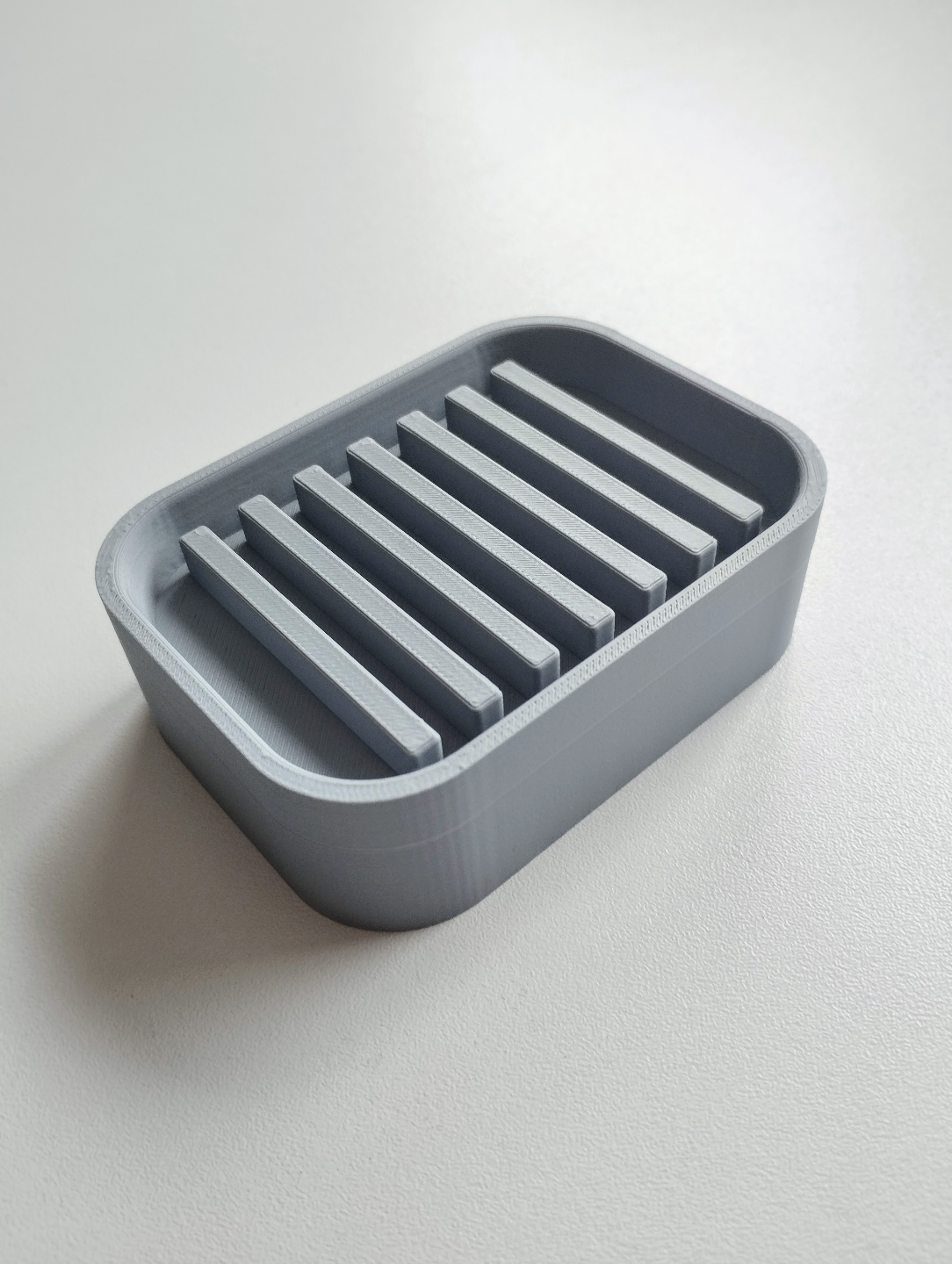 Detail of minimalist soap holder showing drainage slope and refined edge