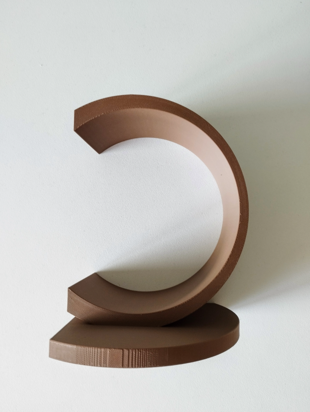 White circular bookend holding stack of books on wooden shelf