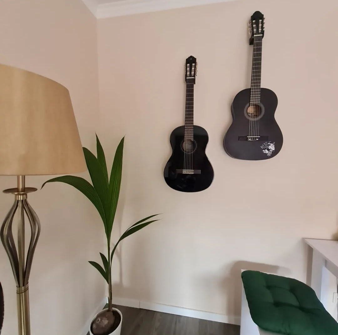 Electric guitar mounted on white wall using discreet minimalist holder