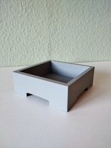 Minimalist bonsai pot holding a small plant, styled on a light wooden shelf